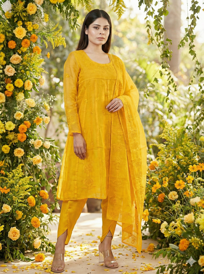 Woman in a yellow traditional outfit standing amidst floral decorations