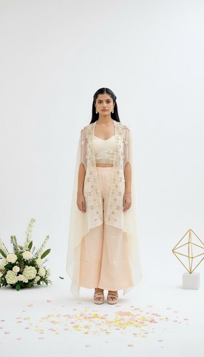 Woman in a peach traditional outfit with white dupatta standing indoors.