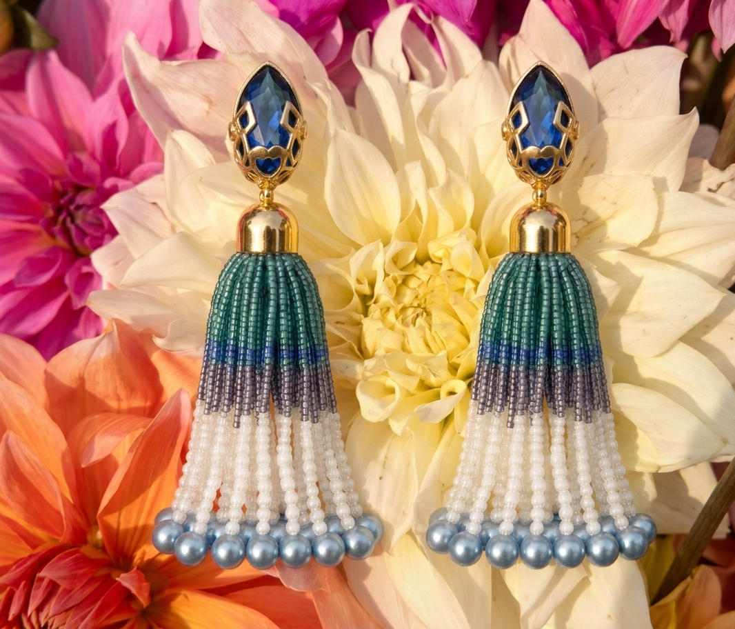 Pair of beaded tassel earrings with blue and green accents on a floral background