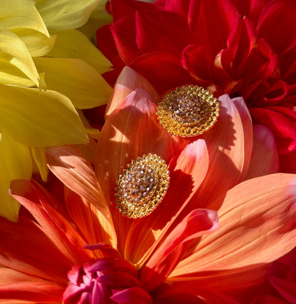 Gold earrings on a vibrant flower background