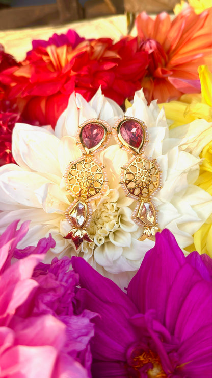 Gold and red earrings on a bed of colorful flowers