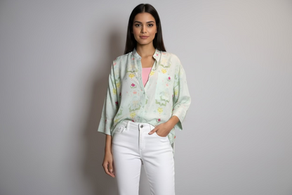 Person wearing a light-colored shirt with floral patterns in an outdoor setting