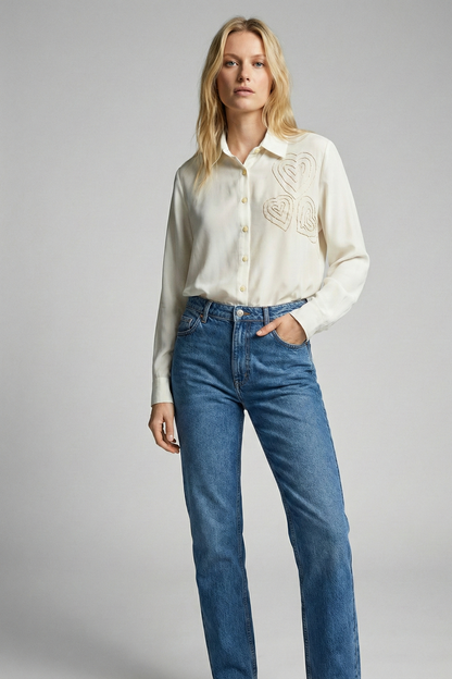 Woman wearing a white blouse and blue jeans on a gray background